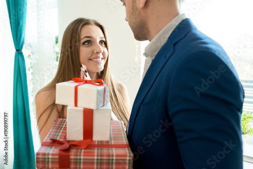 Portrait of beautiful young woman looking lovingly up at her boyfriend receiving gifts for Valentines day