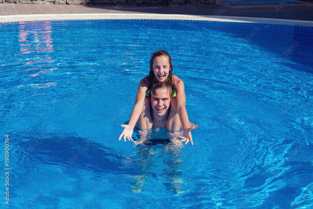 boy and girl having fun in swimming pool