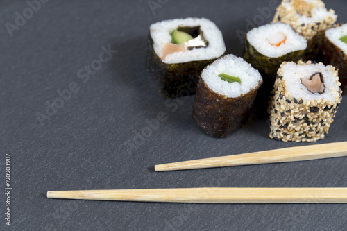 Sushi with chopsticks on black background