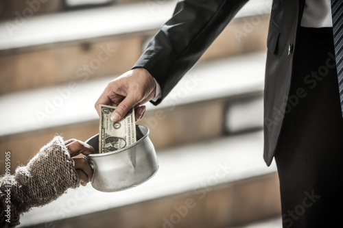 фотографія hand of kind bussiness man giving dollar money to beggar