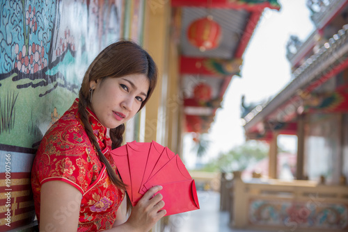 Portrait of beautiful asian woman in Cheongsam dress with Red envelope in hand Thailand people Happy Chinese new year concept