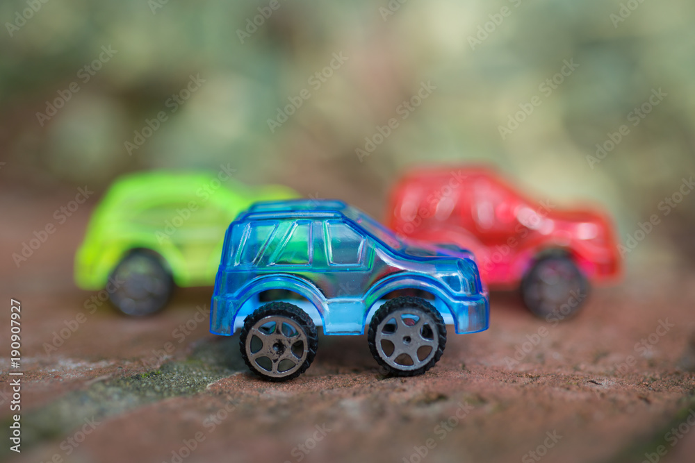 blue red and yellow transparent toy cars on brick wall blue red and yellow transparent toy cars on brick wall