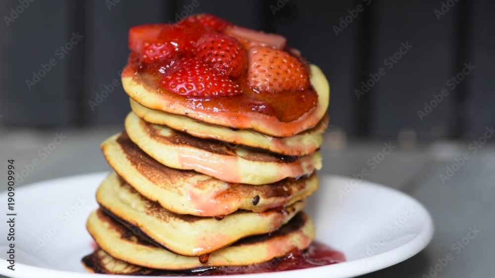 Covering Strawberry Pancakes with dripping red sweet sauce, Delicious breakfast or desert strawberry pancackes, with lots of jam Covering Strawberry Pancakes with dripping red sweet sauce, Delicious breakfast or desert strawberry pancackes, with lots of jam