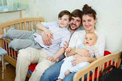 Happy young family with two boys sons in children room. Laughing happy family concept