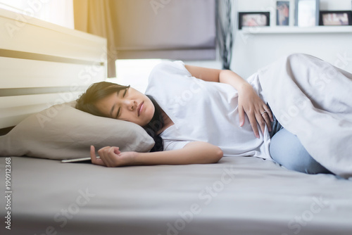 Young woman having painful stomachache,Female suffering from abdominal pain while sleeping