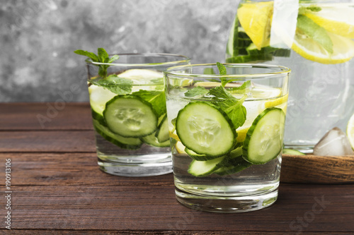 Detox drink with cucumber, lemon and mint in glasses on a wooden background