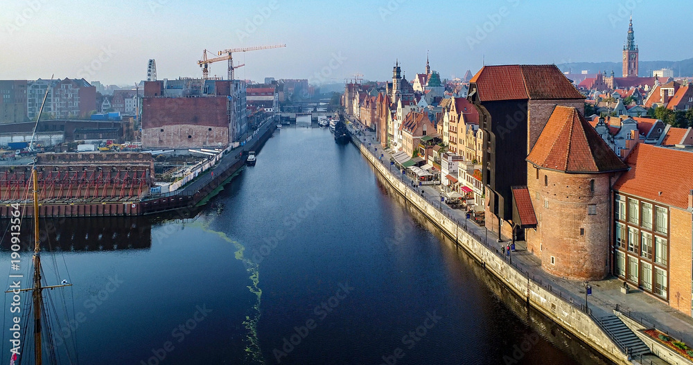 Gdansk, Poland. Old city with the oldest medieval port crane (Zuraw) in Europe, town hall tower, Motlawa River, bridges, World War II ruins, building site. Aerial view, sunrise light.