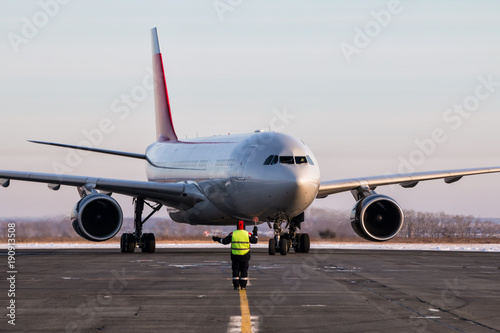 Airport ground crew meets passenger airplane that taxiing to the parking place in a cold winter weather
