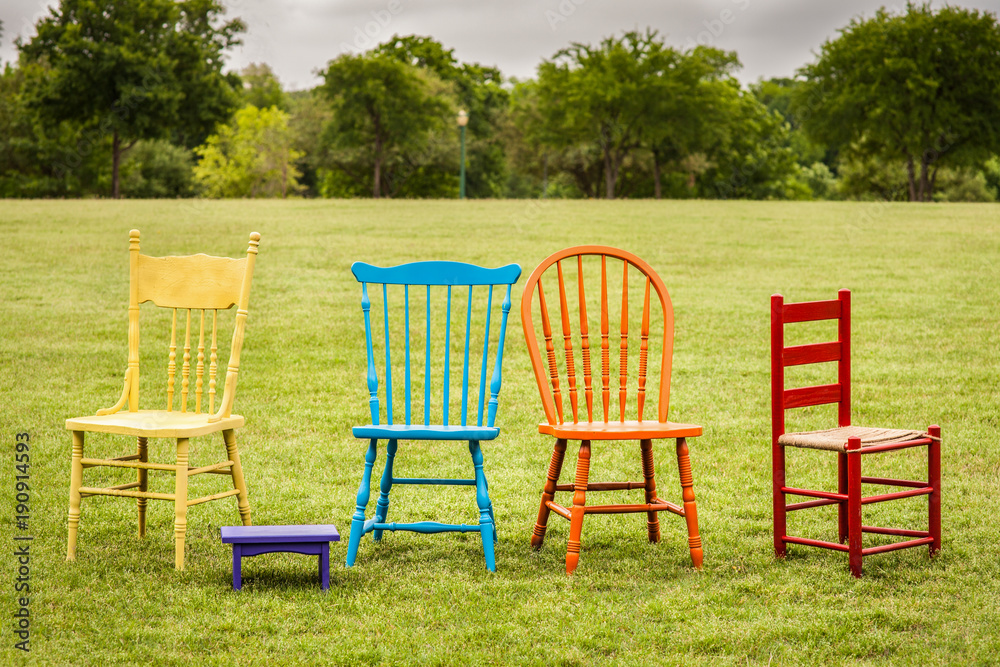 colored chairs in an open field at spring time colored chairs in an open field at spring time