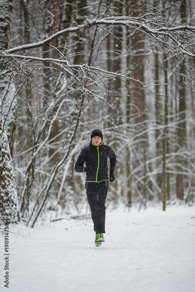 Picture of man in sportswear, black hat jogging in winter