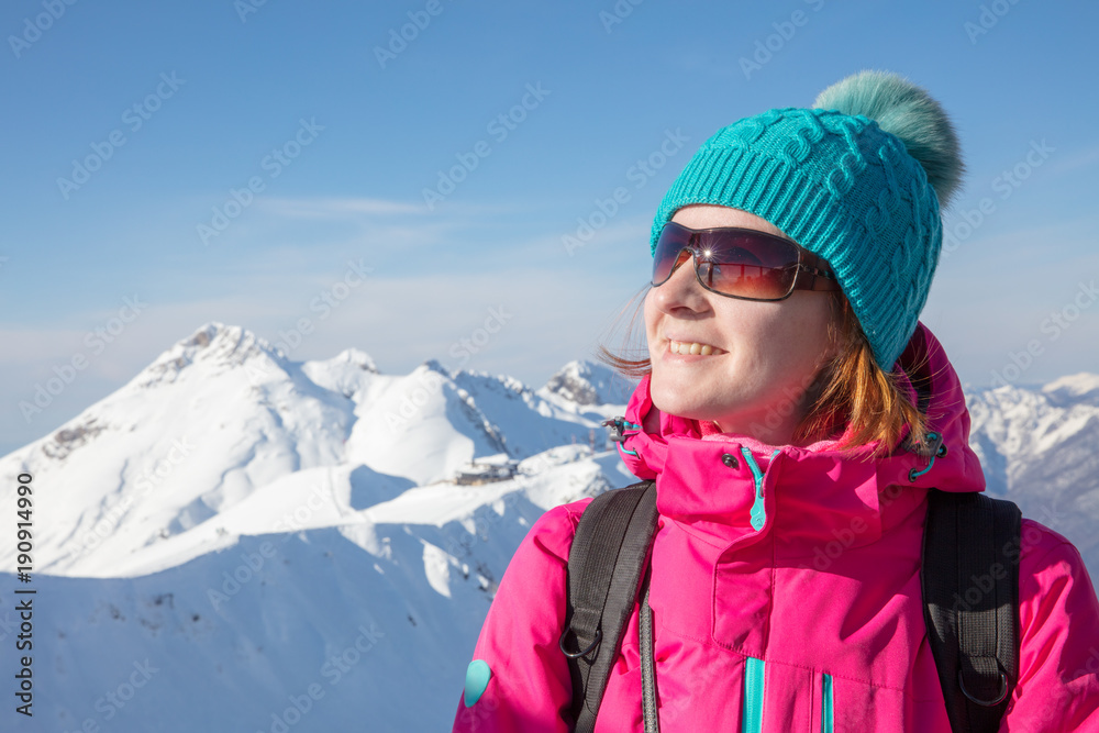 portrait of smiling young woman in blue hat on background snowy mountain portrait of smiling young woman in blue hat on background snowy mountain