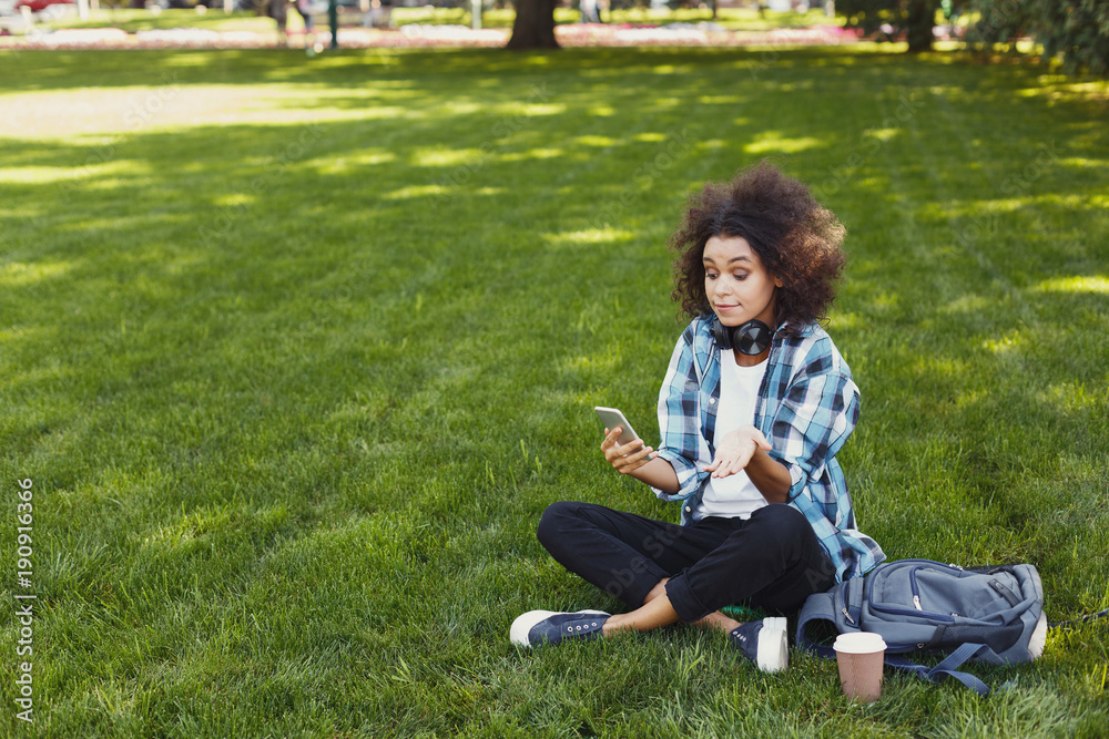 Frustrated black girl with smartphone in the park Frustrated black girl with smartphone in the park