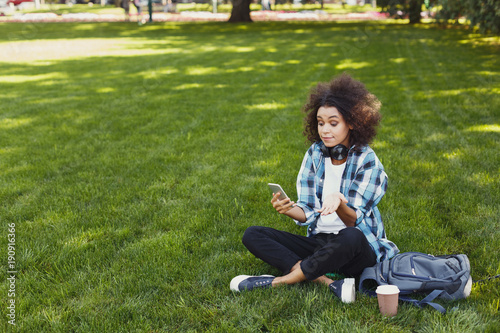 Frustrated black girl with smartphone in the park © Prostock-studio