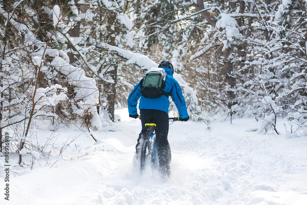 Fototapeta premium Cyclist in Blue Drifting on Mountain Bike in Beautiful Winter Forest. Extreme Sport and Enduro Biking Concept.