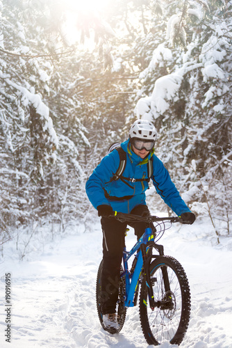 Cyclist in Blue Riding the Mountain Bike in Beautiful Sunny Winter Forest. Extreme Sport and Enduro Biking Concept.