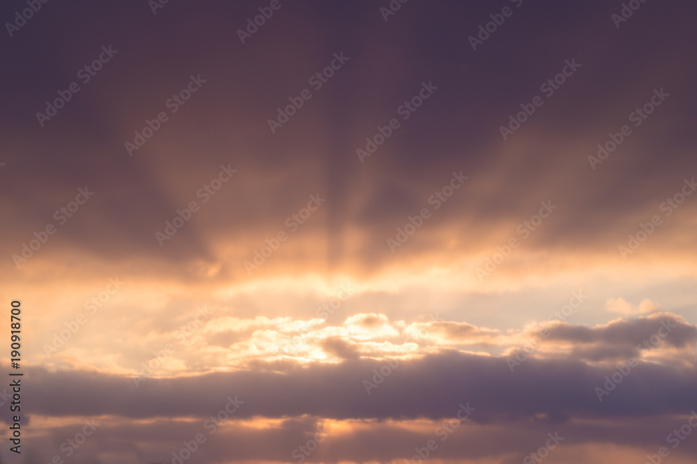 Bright purple clouds with sunbeams at sunset or sunrise