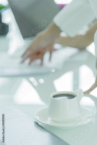 A coffee cup with white plate on the office desk.