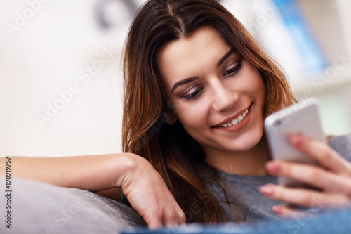 Happy adult woman using phone at home in the living room