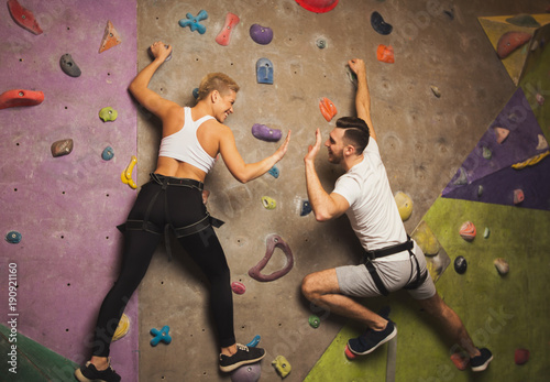 Two professionals climbing artificial rock wall at gym