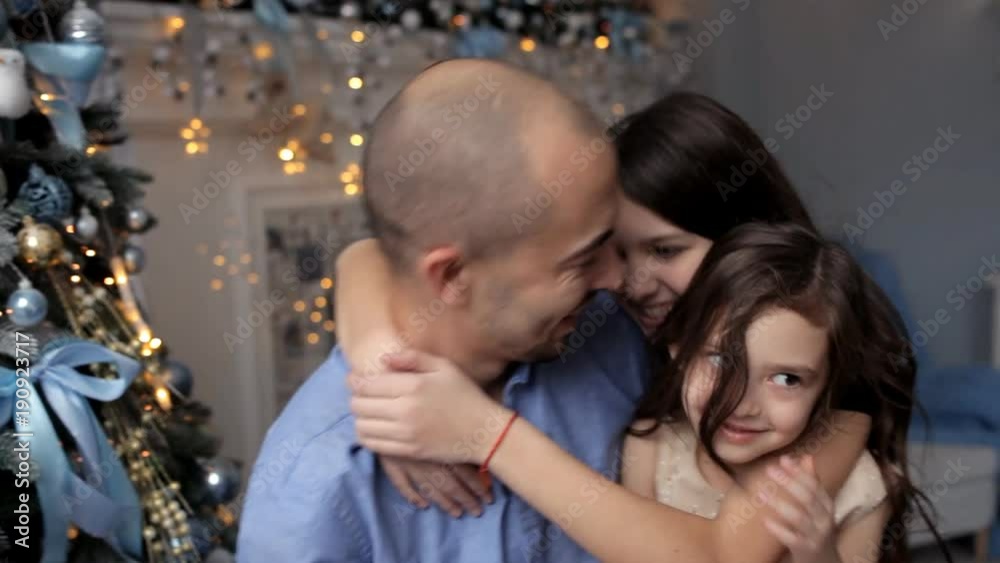 Father hugging daughter near Christmas tree Father hugging daughter near Christmas tree