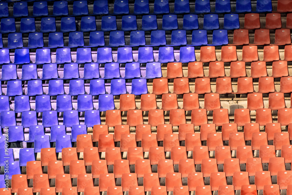 Obraz premium Orange and blue empty chairs at the football stadium