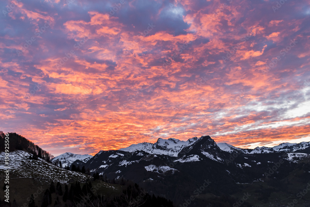 Orange sky at sunset over the snow covered mountains, Switzerland, Swiss Alps