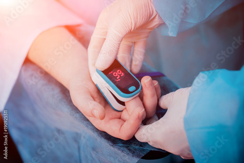 Pulse oximeter on the patient's hand photo