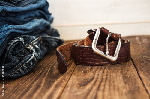 A stack of jeans on a wooden background and a belt photo