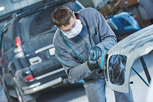 auto repairman grinding autobody bonnet