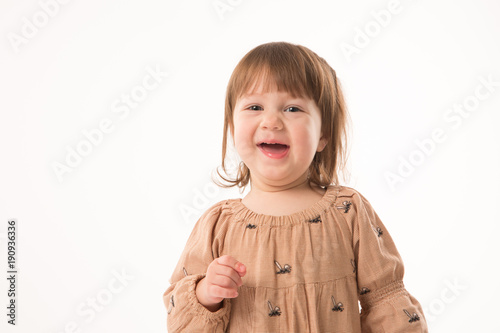 Cute little girl in beige dress isolated on white background. Portrait of happy little girl on white background. Sweet girl with curly hair.