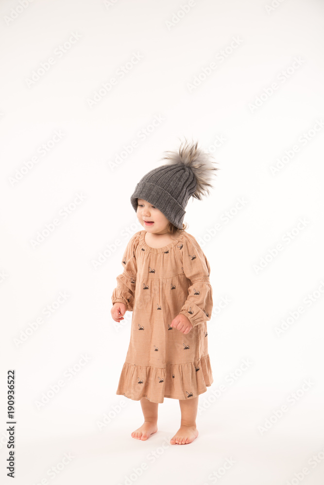 Portrait of happy little girl. Cute little girl in beige dress in a gray hat isolated on white background. Portrait of happy little girl. Cute little girl in beige dress in a gray hat isolated on white background.