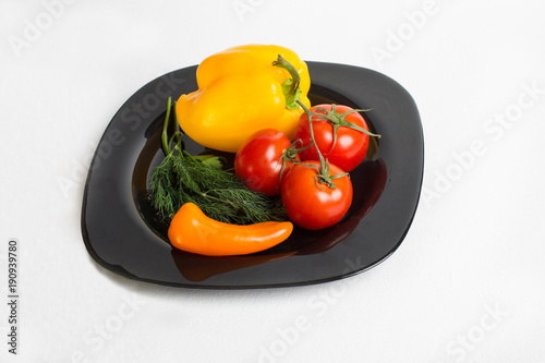 fresh vegetables lie on a black plate