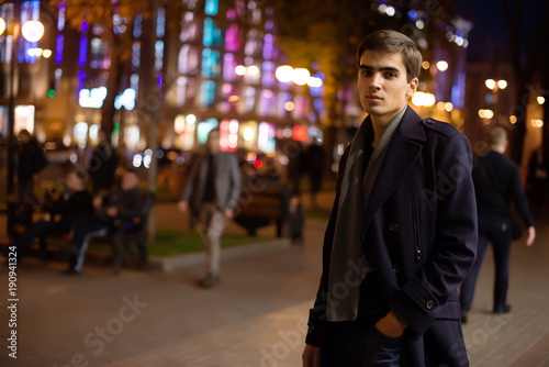 The guy walks around the night city. Portrait of a young funny guy.