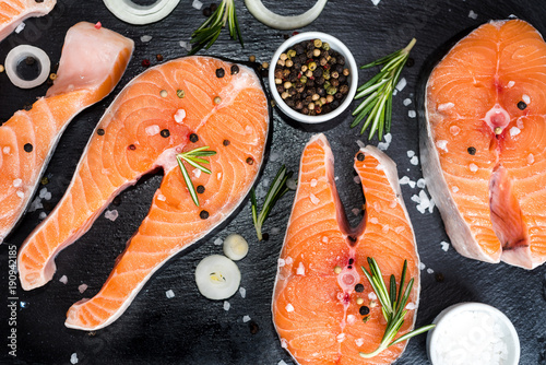 Raw salmon steaks on the dark stone background photo