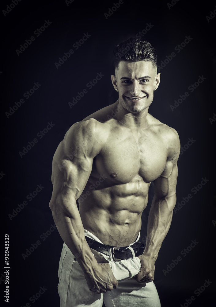 Good Looking Young Gym Fit Man Showing His Sexy Six Pack Abs While Looking at the Camera. Isolated on Black Background. Good Looking Young Gym Fit Man Showing His Sexy Six Pack Abs While Looking at the Camera. Isolated on Black Background.