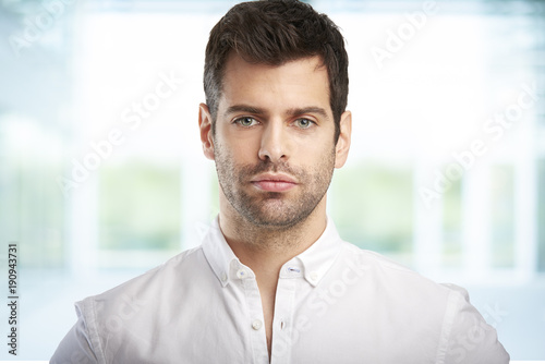 Young man portrait. Portrait of handsome young businessman looking at camera while standing at office.