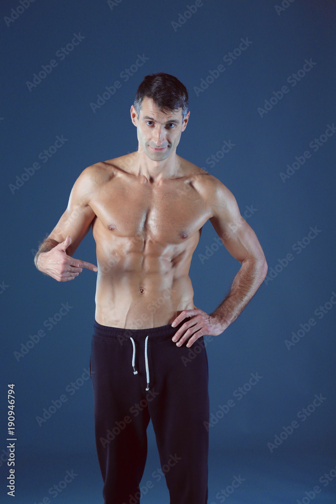 Fototapeta premium muscular man. Muscular man on a grey background showing muscles. Fitness instructor. Fitness professional. Workout. Men's fitness.