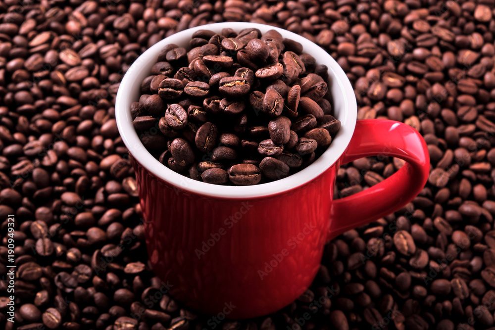 Fototapeta premium Red coffee cup mug one single for espresso or capuccino filled full of coffee beans on a background of scattered dark coffee beans photo 