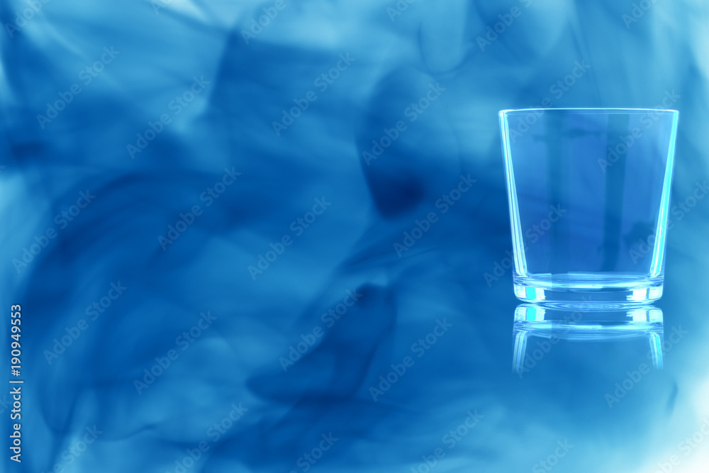 Empty glass of whiskey enveloped in blue smoke. Empty glass of whiskey enveloped in blue smoke.