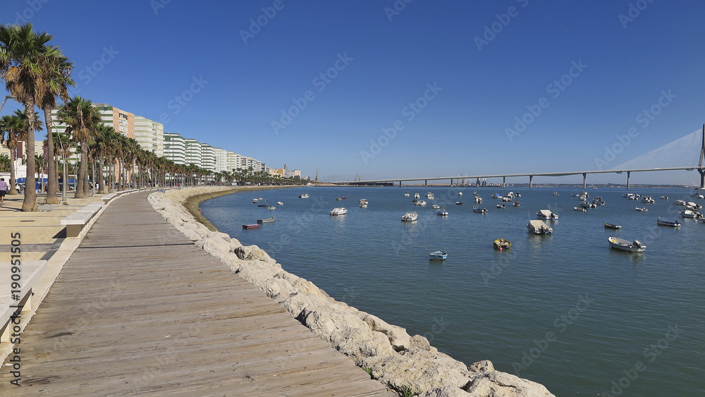 horizontal view of seafront promenade and small wooden boats in the port of cadiz, spain