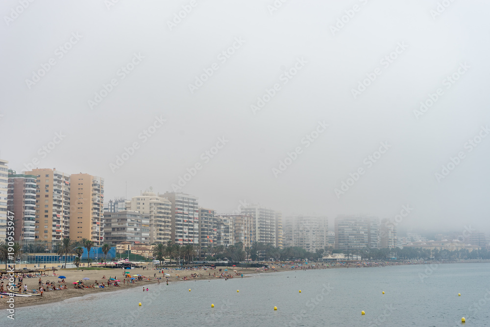 Obraz premium The building along the coastline at Malagueta beach covered by fog in Malaga, Spain, Europe
