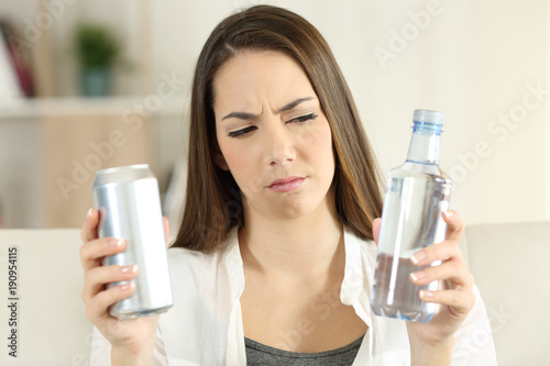 Woman doubting between soda drink and water