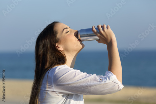 Woman refreshing drinking soda on the beach