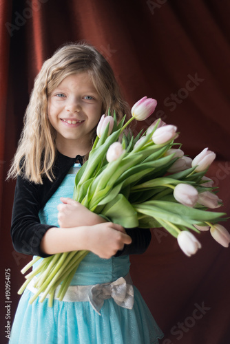 Adorable smiling little Caucasian girl with bouquet of tulip flowers
