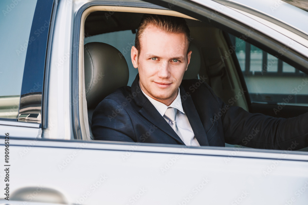 Handsome businessman in suit in a car