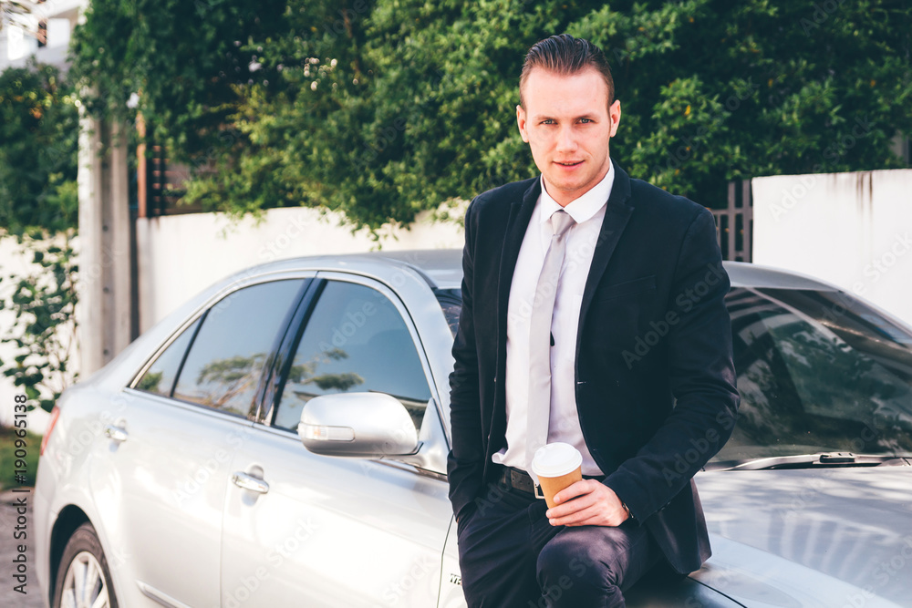 Handsome businessman standing with coffee cup near the car Handsome businessman standing with coffee cup near the car