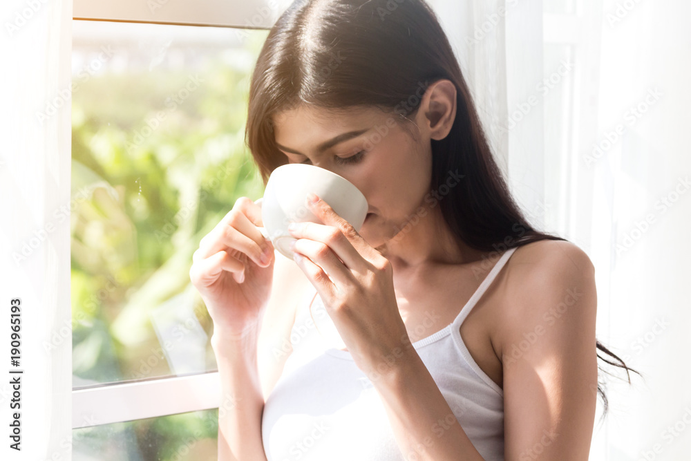Woman drinking coffee in bedroom in the morning Woman drinking coffee in bedroom in the morning