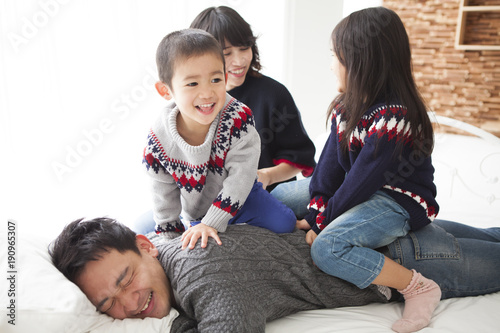 寝ているお父さんの上に乗って はしゃいでいる 娘と息子 お母さんが笑顔で見守っている Stock 写真 Adobe Stock