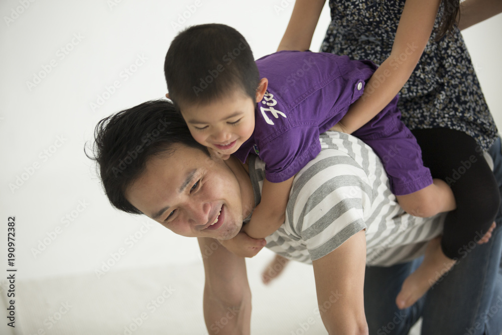 男の子と女の子が、お父さんとお馬さんごっこをしている。 男の子と女の子が、お父さんとお馬さんごっこをしている。