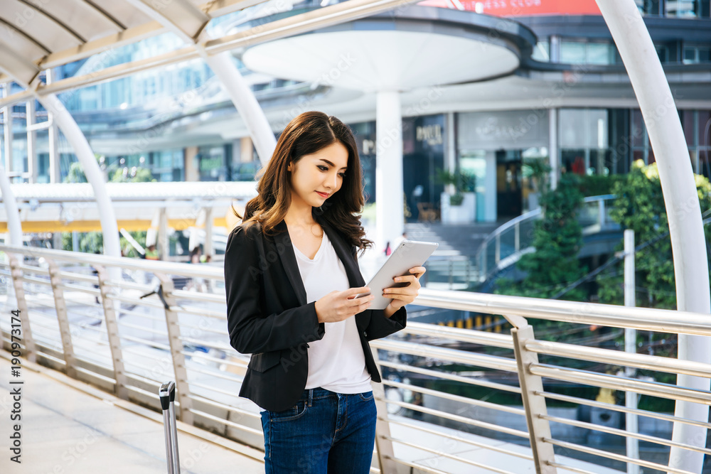 Attractive business woman using a digital tablet while standing in front of office building. Attractive business woman using a digital tablet while standing in front of office building.